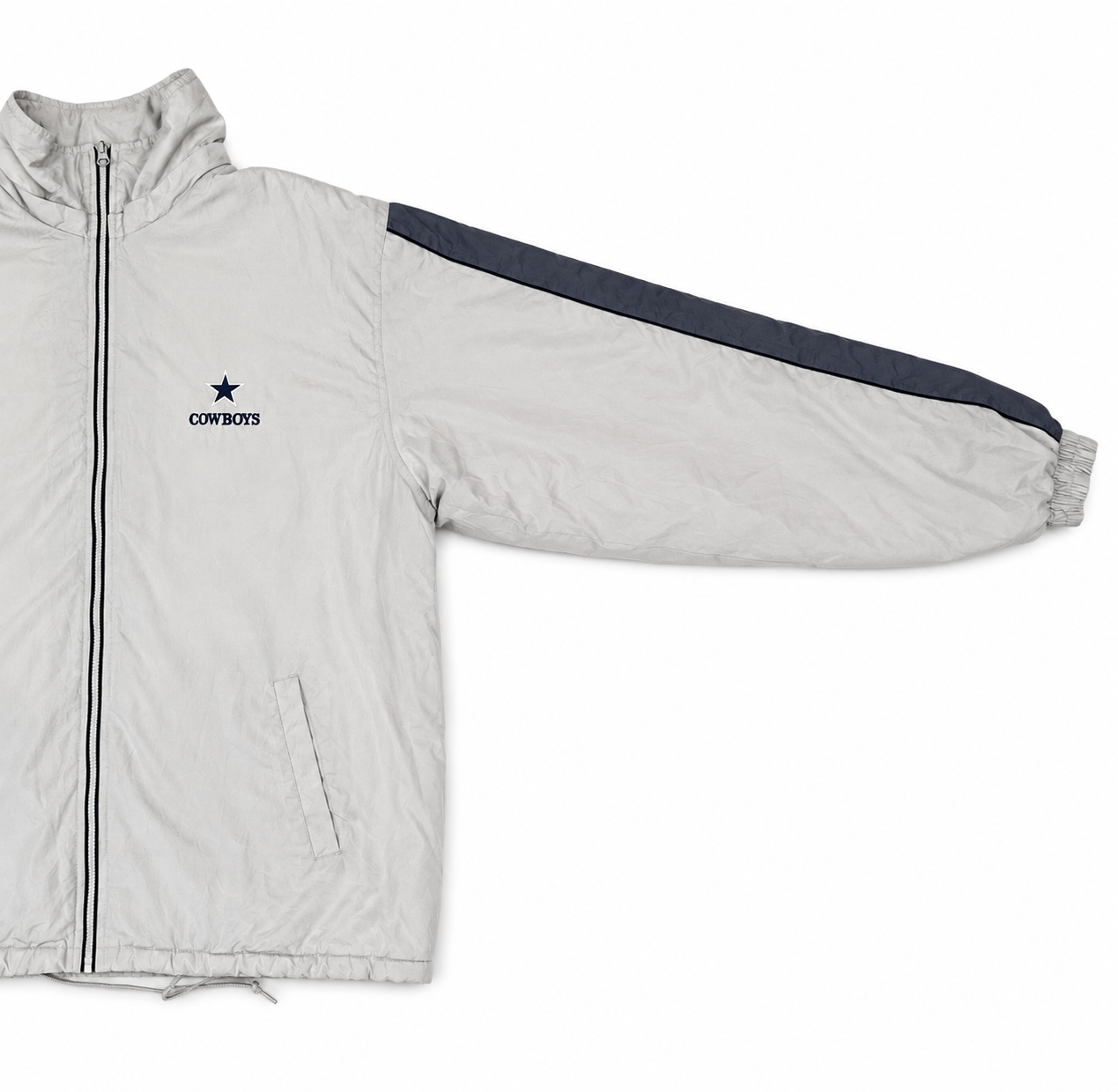 A light tan Dallas Cowboys windbreaker jacket with a dark navy blue sleeve stripe and matching navy logo on the chest, displayed on a clean white background.