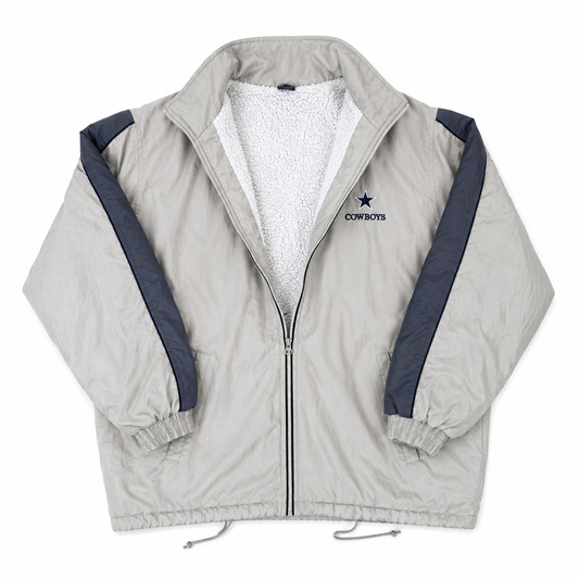 A light tan zip-up windbreaker jacket with a white sherpa lining, navy blue sleeve stripes, and a Dallas Cowboys logo on the left chest, displayed flat against a white background.