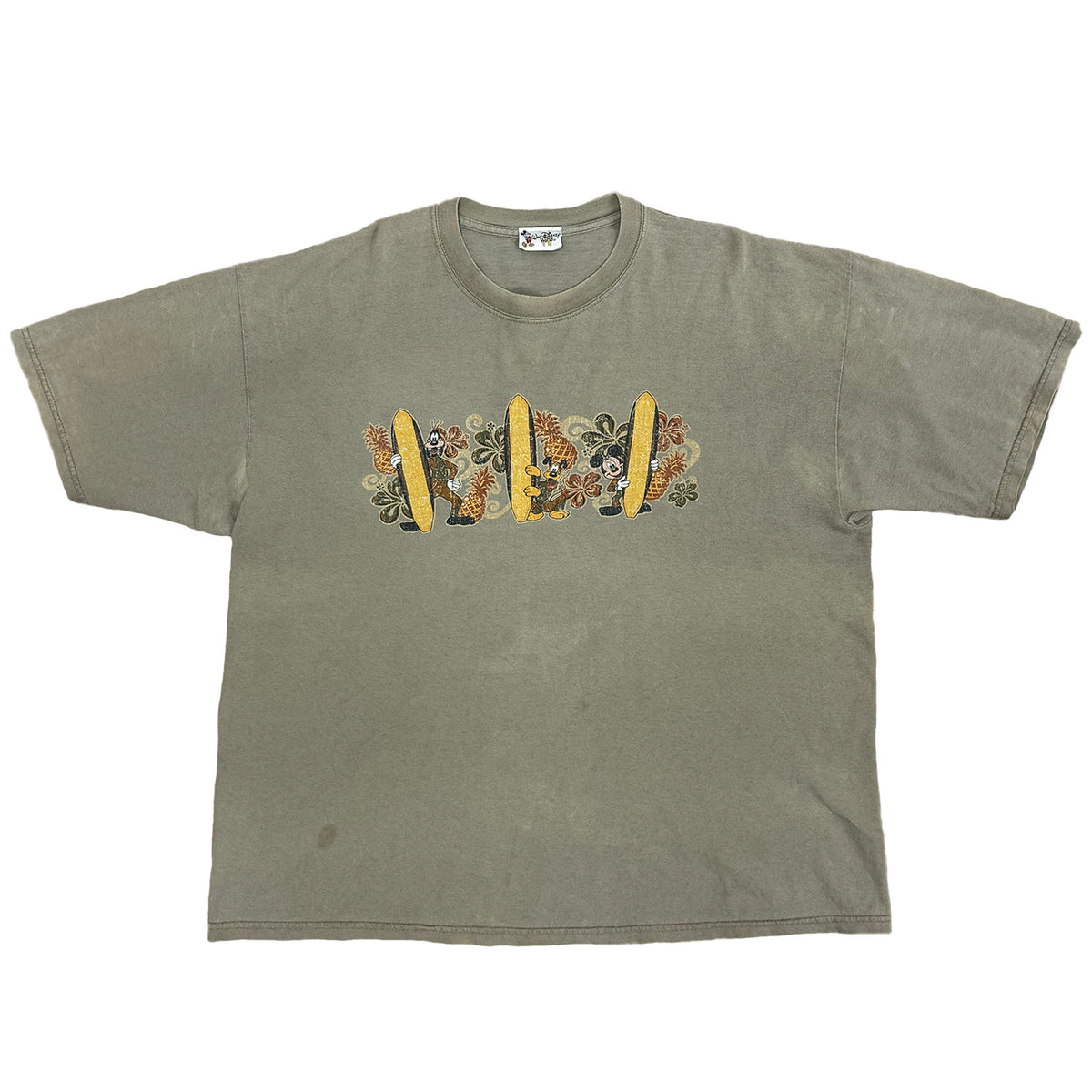 TAN SHIRT WITH MICKEY MOUSE, PLUTO, AND GOOFY HOLDING SURFBOARDS WITH FLOWERS AND PINEAPPLES IN BACK GROUND SHORT SLEEVE SHIRT.