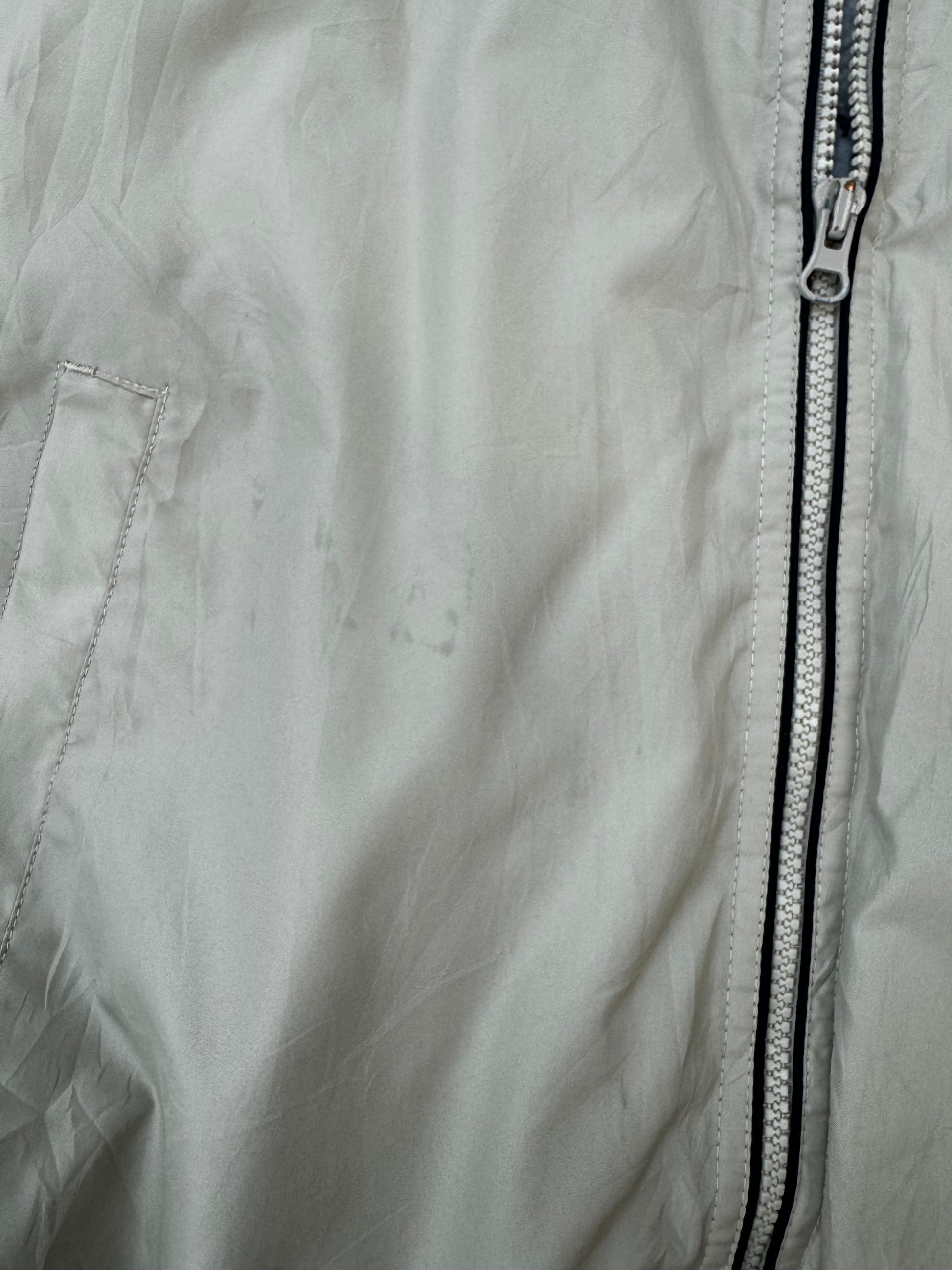 Close-up of a light tan lightweight jacket fabric with a vertical silver zipper and a side seam pocket.