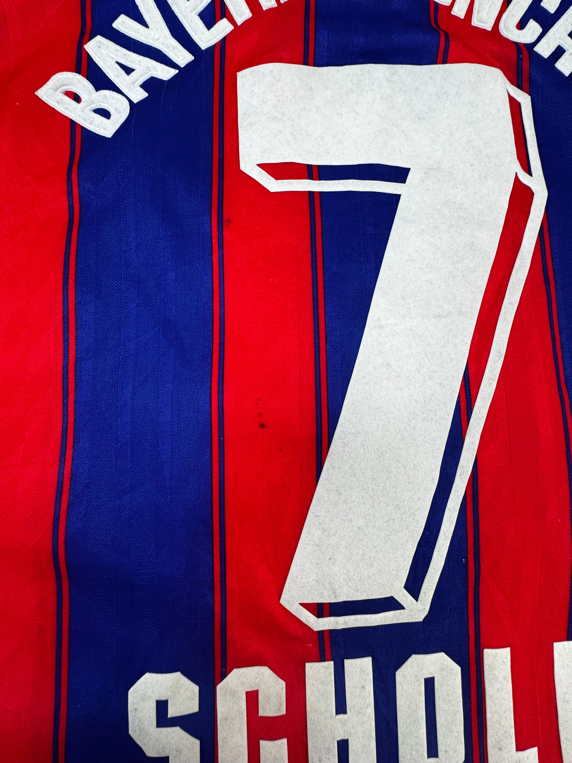 Close-up of the back of a red and blue striped Bayern Munich jersey with the number 7 and the name Scholl in white.